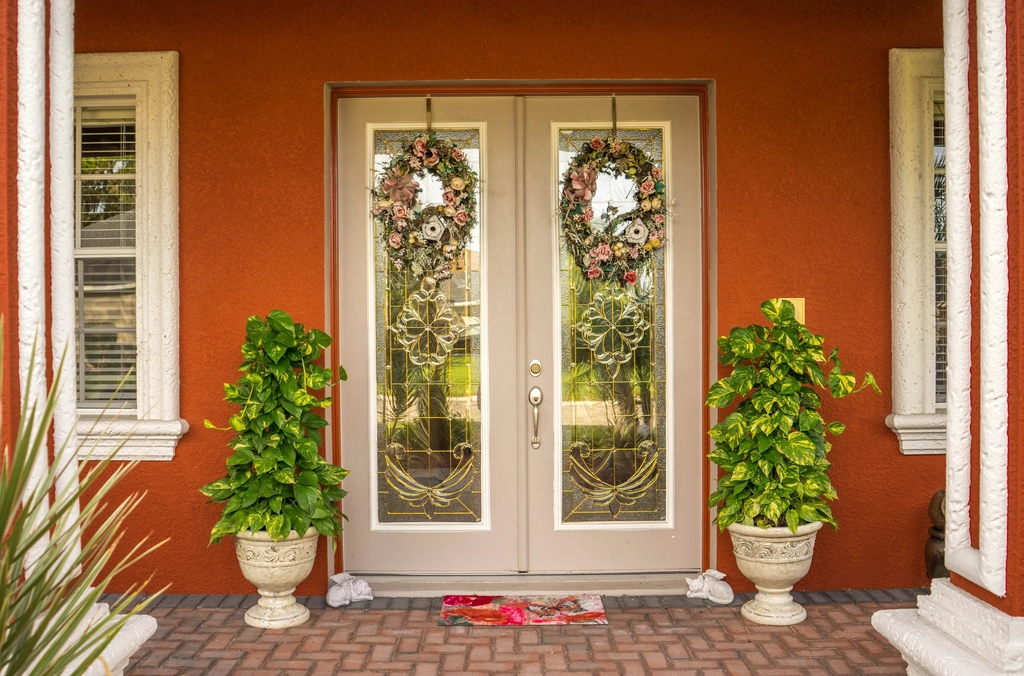 Front door with wreaths and potted plants